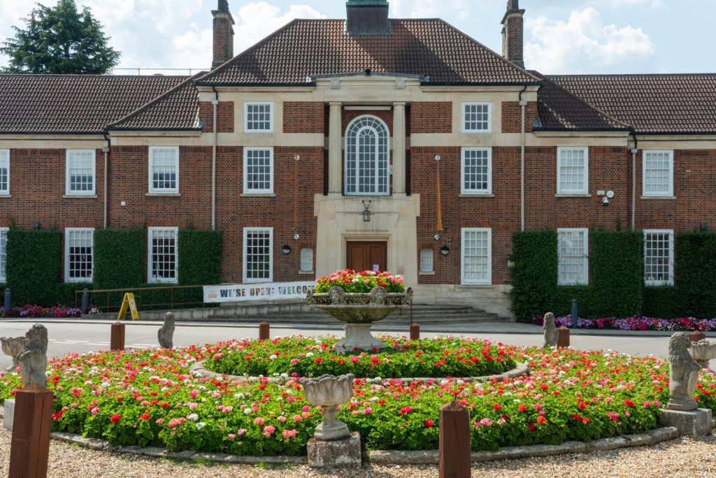 A grand red-brick building in Art Deco style, with a white stone surround to the large front door.