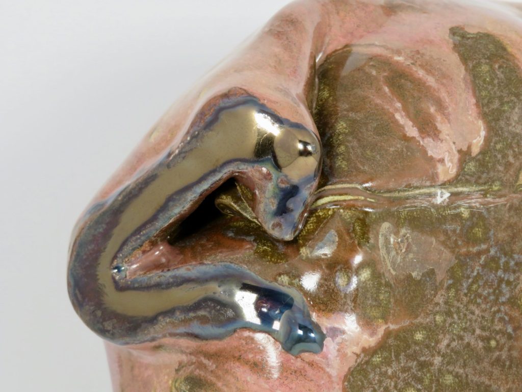 Close-up detail of a ceramic sculpture. The clay has been folded into a non-regular shape and it has a shiny glaze.